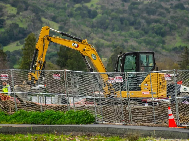 Excavator behind a safety fence at a construction site